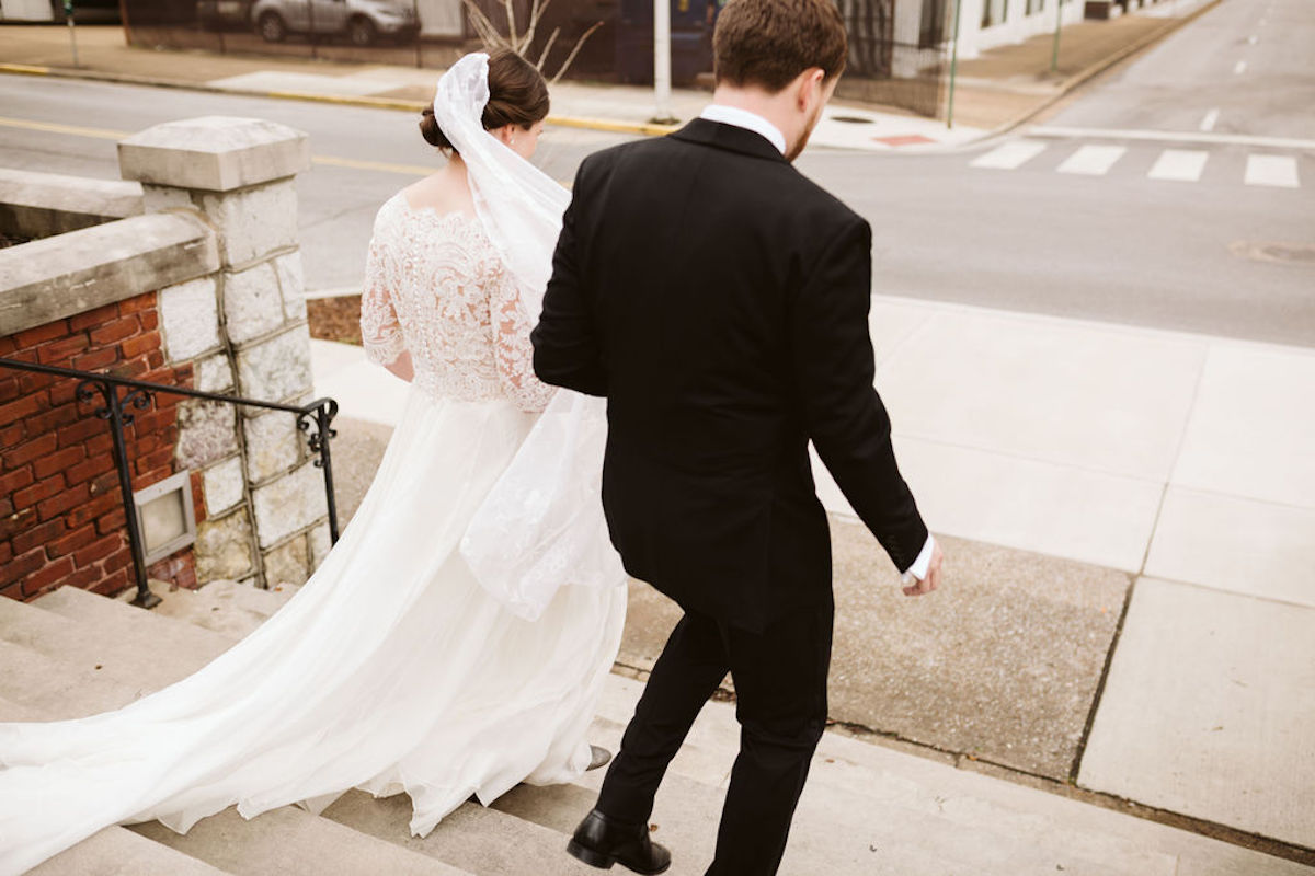 Bride and groom descending cement steps toward sidewalk