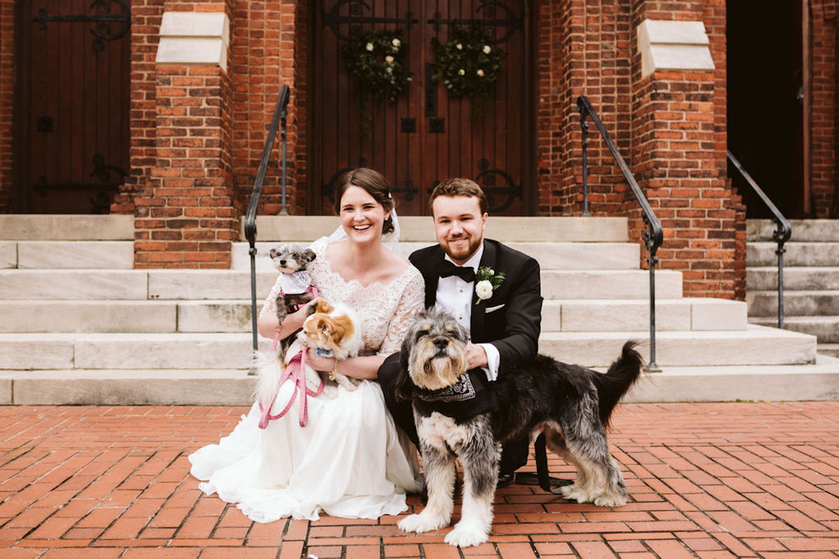 Bride and groom hold their family dogs in front of St Paul's Episcopal Church