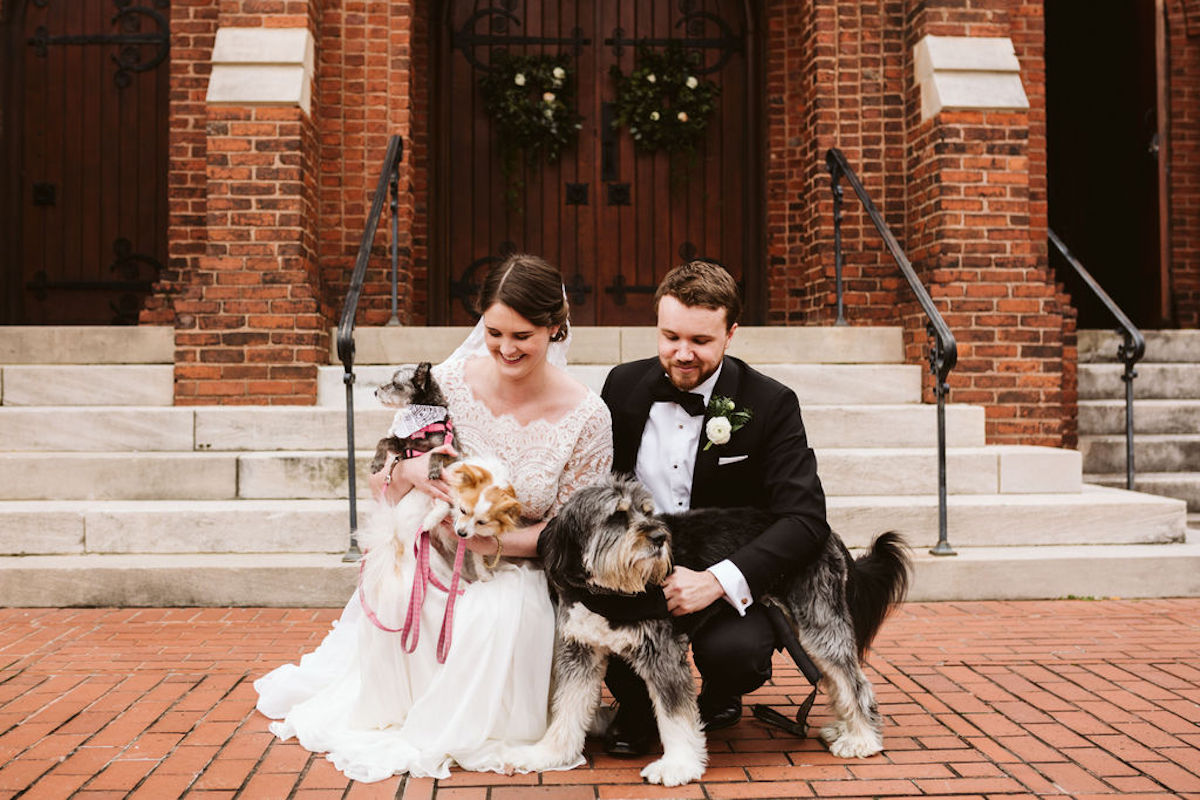 Bride and groom hold their family dogs in front of St Paul's Episcopal Church