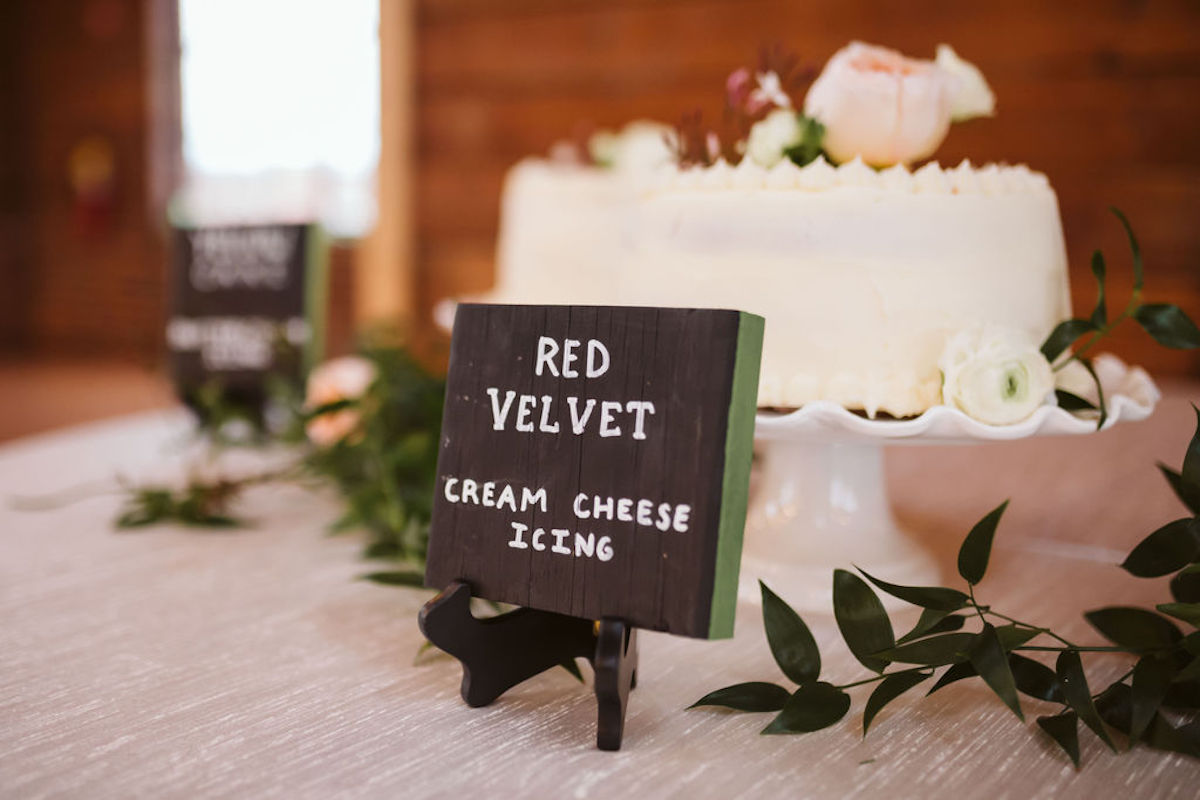Tabletop sign printed with "Red velvet cream cheese icing" in front of white frosted cake