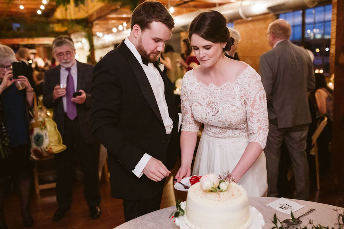Bride and groom hold a plate of bright red red velvet cake for their first taste at their wedding at The Turnbull Building