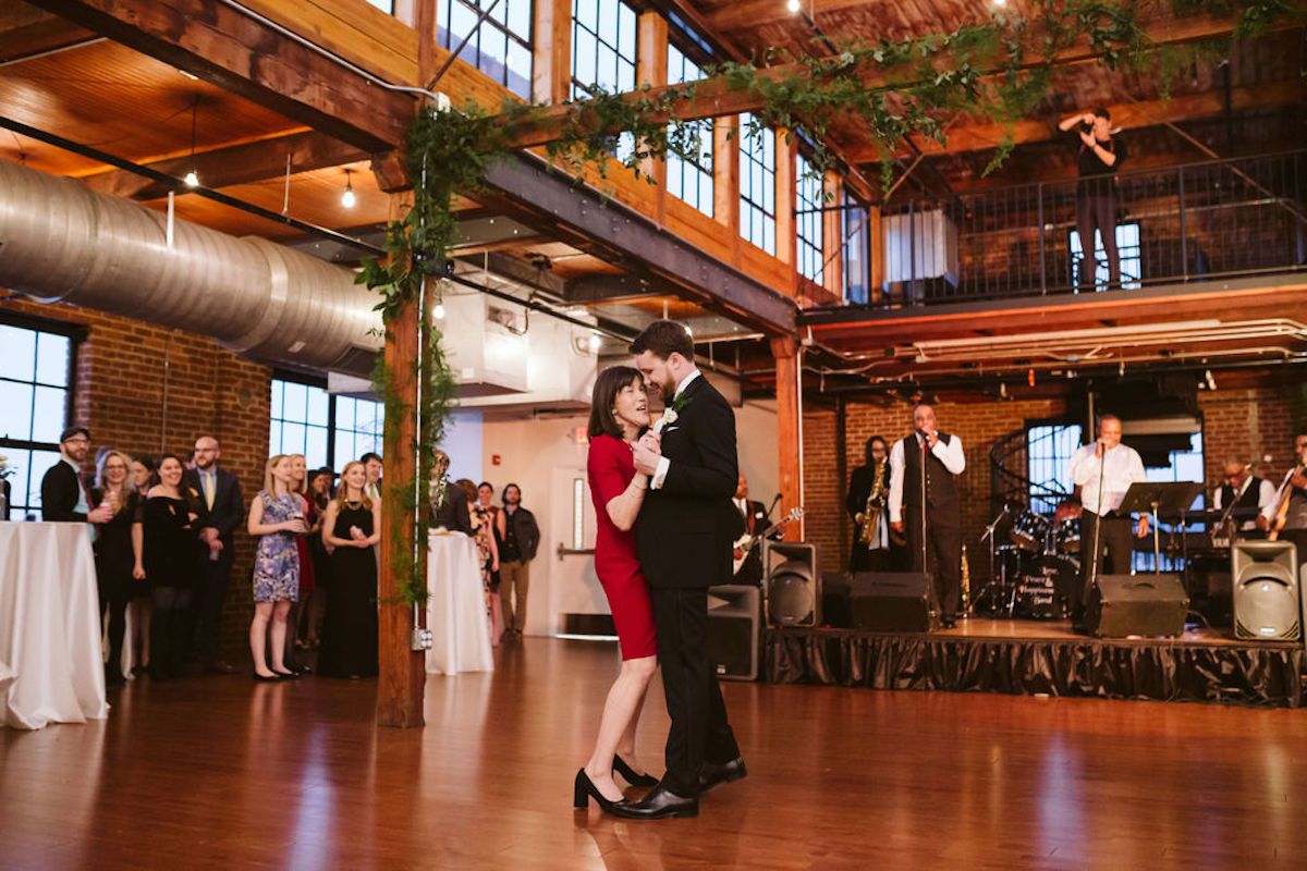 Groom and his mother dance under exposed beams and ductwork at wedding at The Turnbull Building in Chattanooga TN