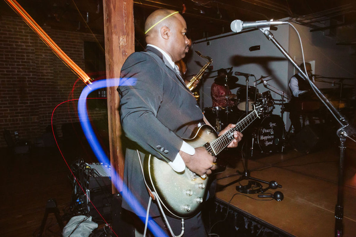 Man plays electric guitar while wearing a yellow glow stick as a halo