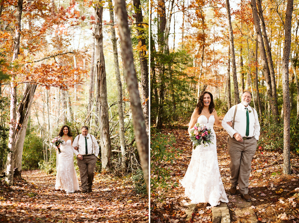 Bride and father walk down a leaf-strewn trail under tall trees with bright autumn leaves