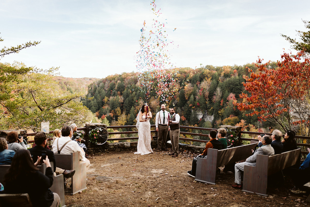 bride and groom shoot off confetti cannons toward their wedding guests at their autumn wedding at Fall Creek Falls overlook