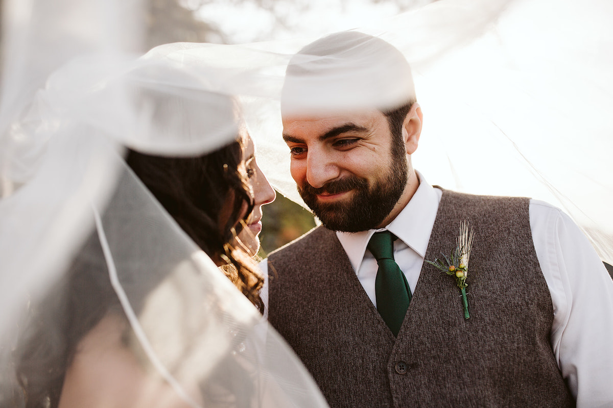 groom smiles at bride under her veil