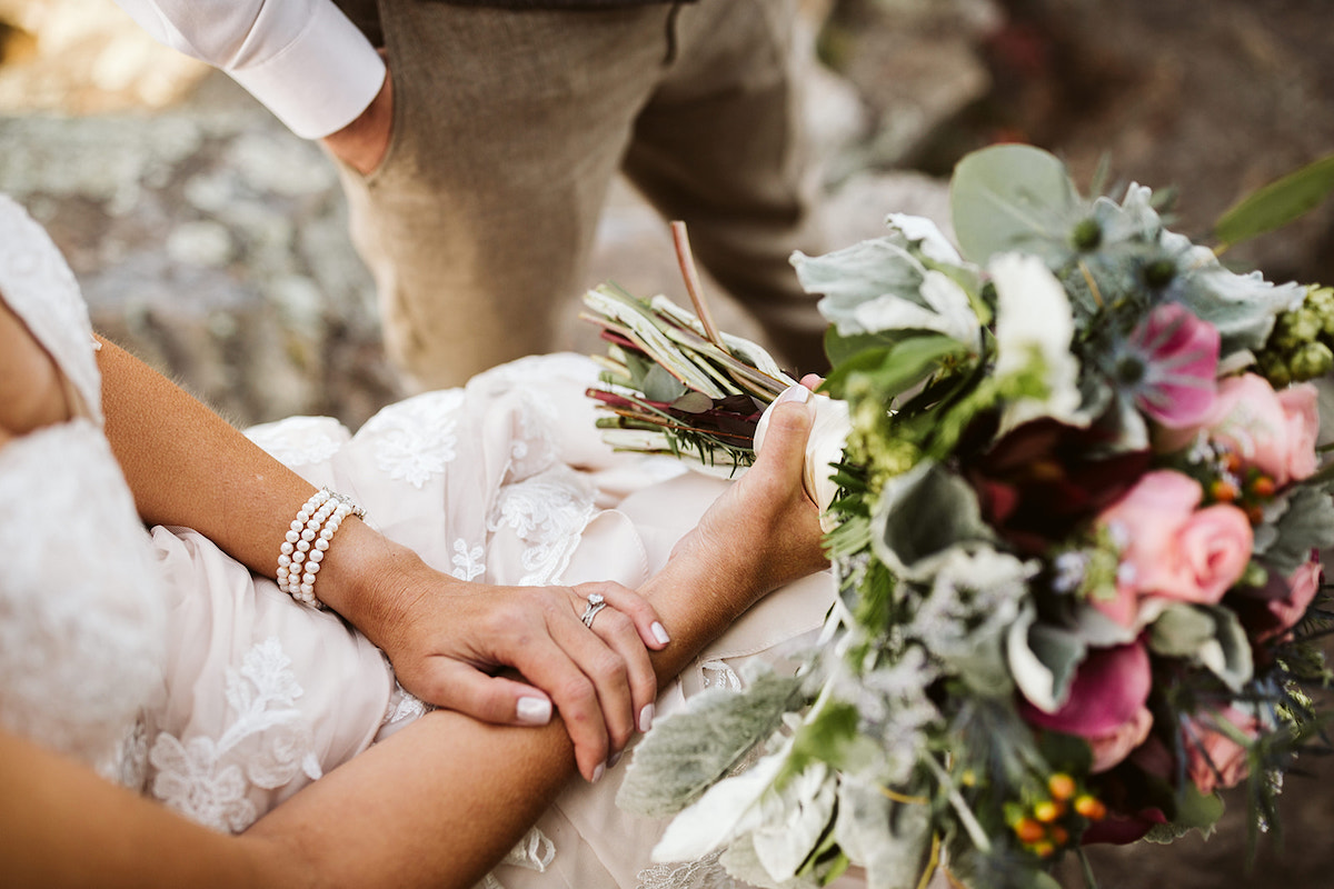 Bride holds her colorful bouquet in her lap