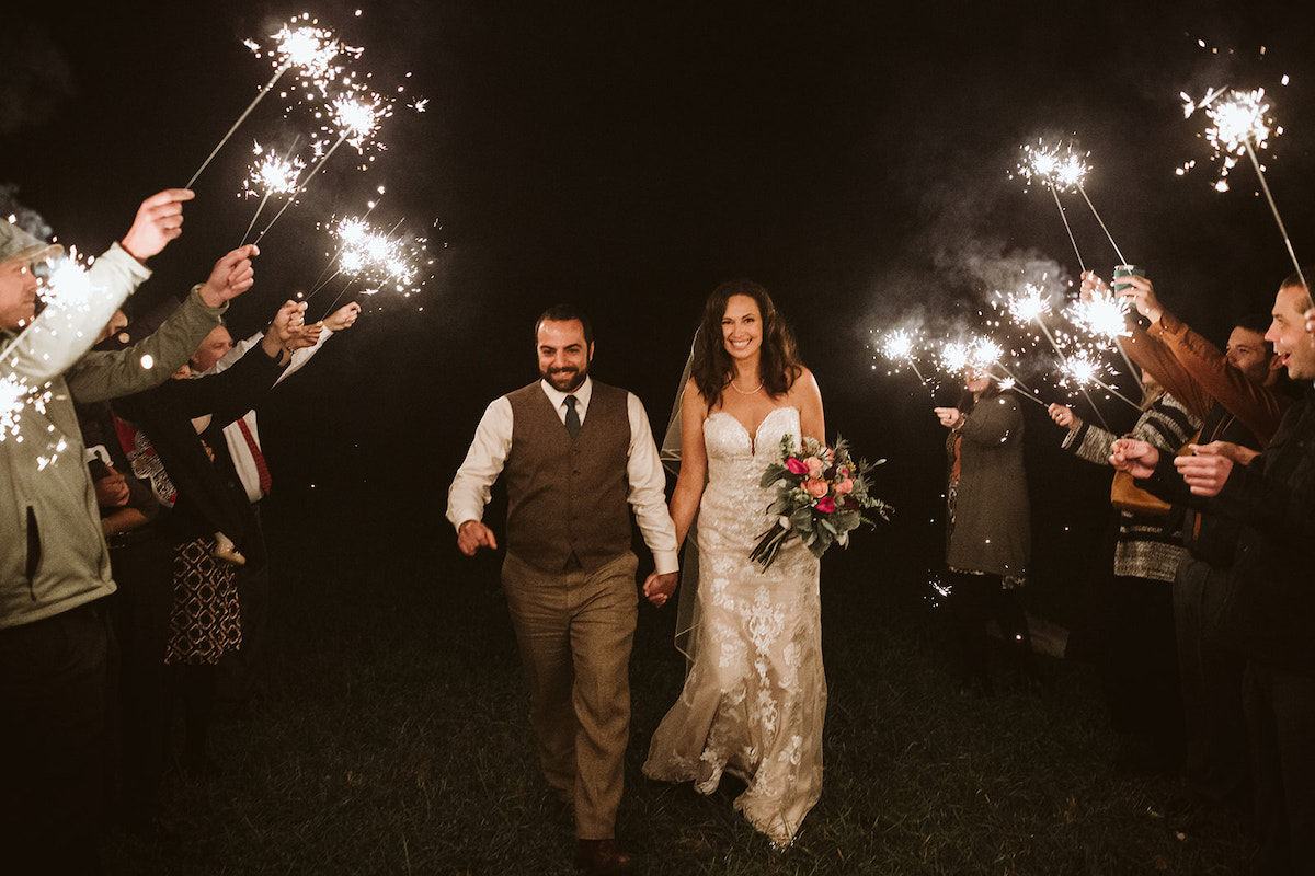 Bride and groom walk through sparkler tunnel