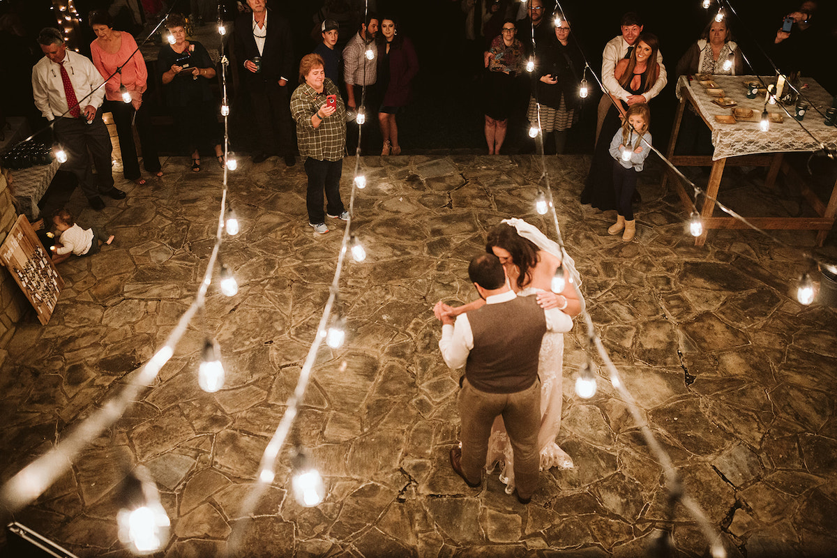 Bride and groom dance on stone patio under string white lights