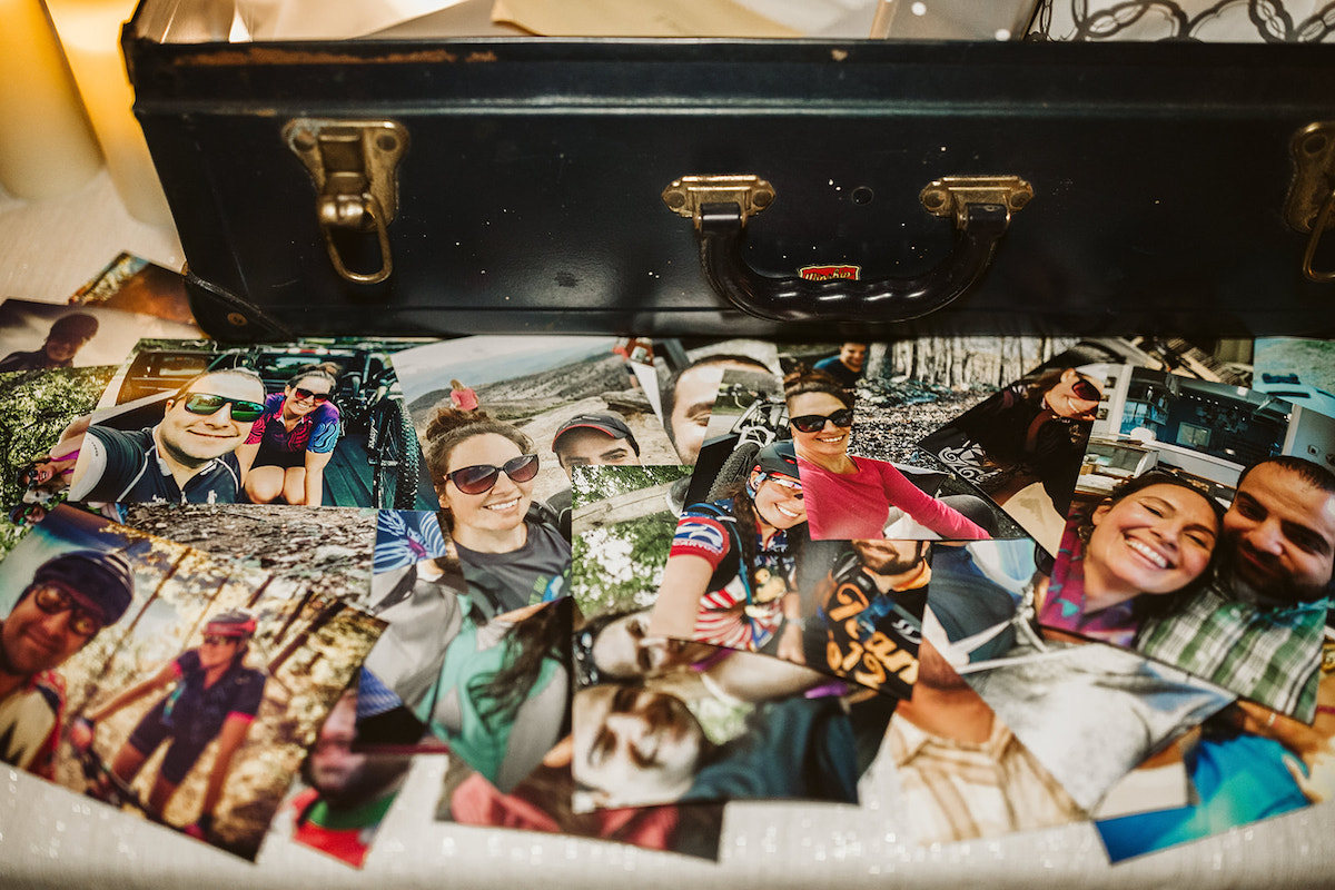 photos of the bride and groom on adventures lie on the gift table near an open suitcase