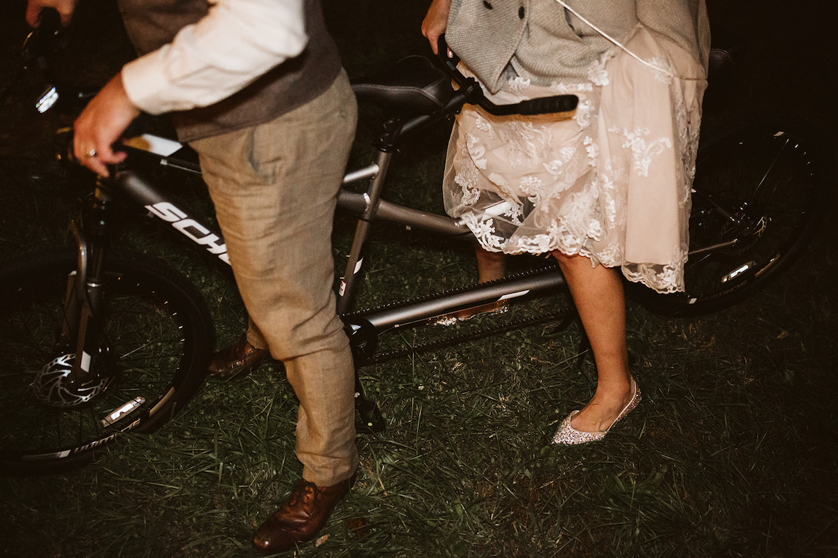 bride and groom stand astride tandem bicycle
