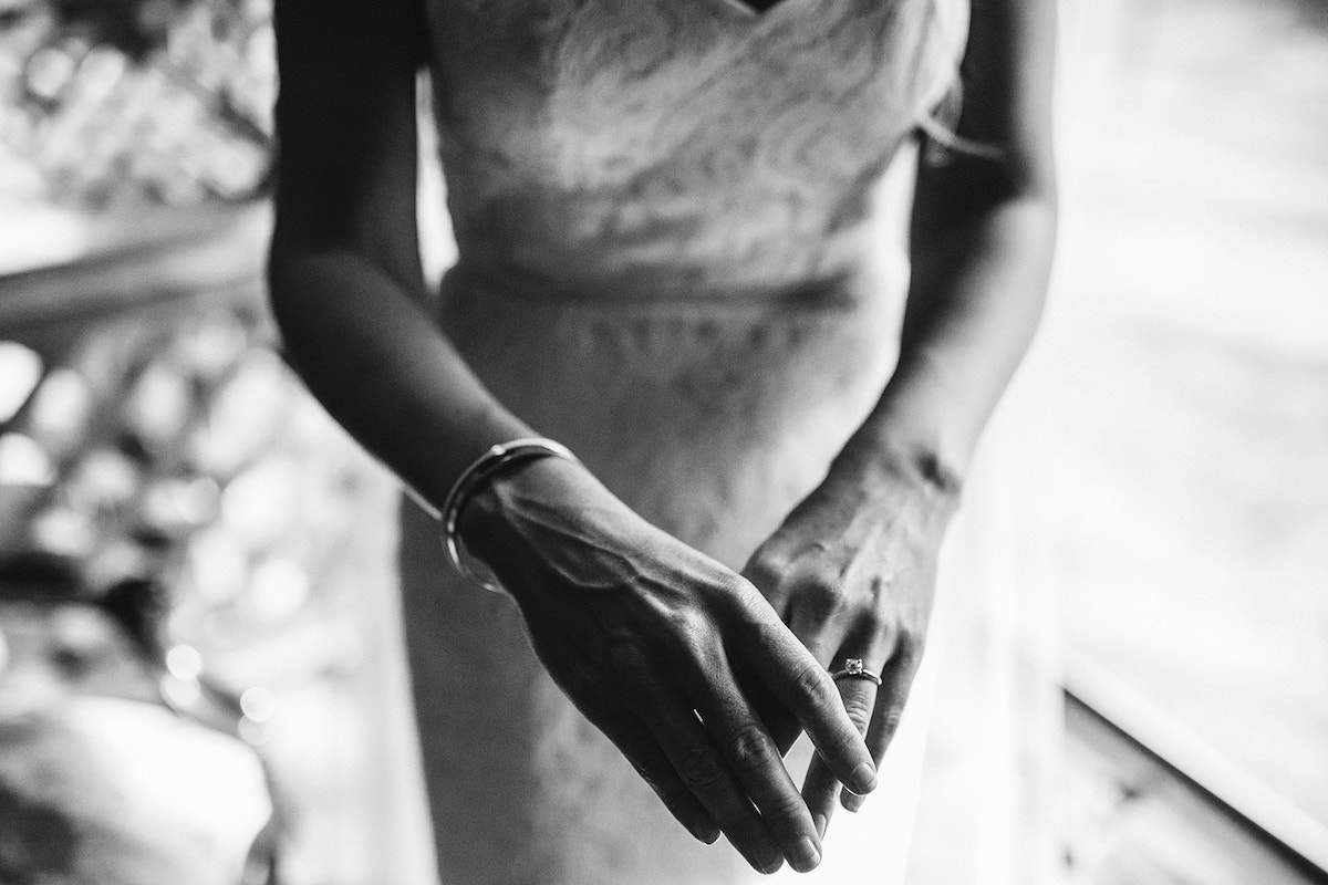 brides hands with simple bracelet around her wrist and engagement diamond ring on her finger