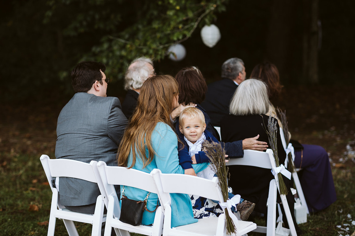 toddler boy sits with woman in white folding chairs