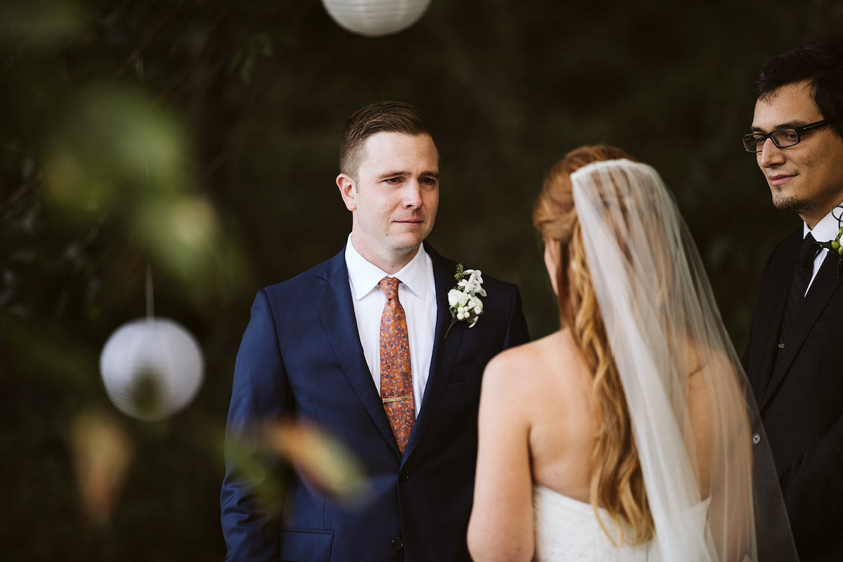 groom looks at bride while she reads vows to him. officiant looks on.