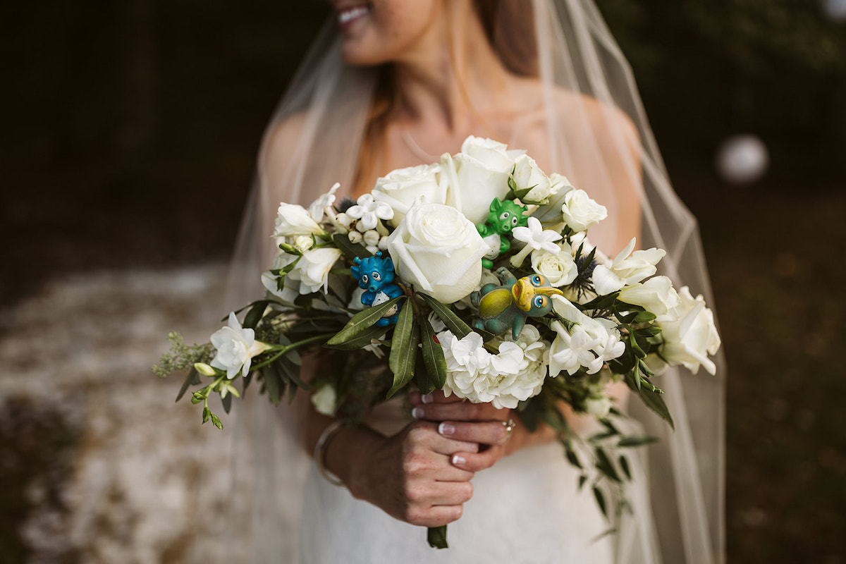brides white floral bouquet with greens and small dinosaur toys