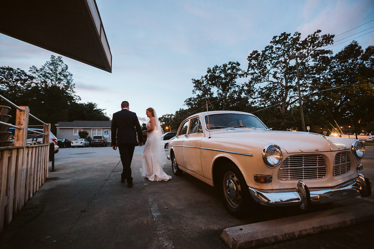 Bride and groom exit white antique Volvo