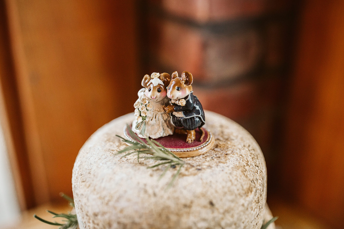 Ceramic bride and groom mice sit on top of thick wheel of cheese