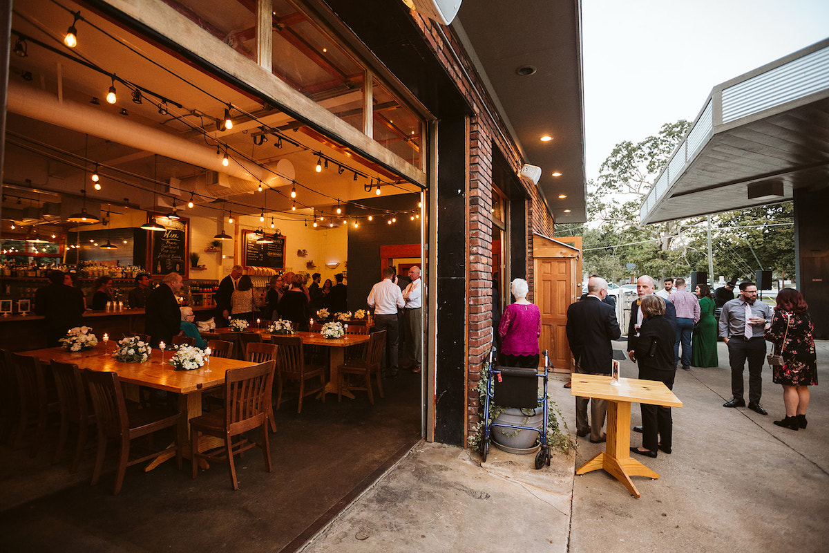 guests gather at The Daily Ration. The garage doors are wide open, allowing people to flow from inside to outside.