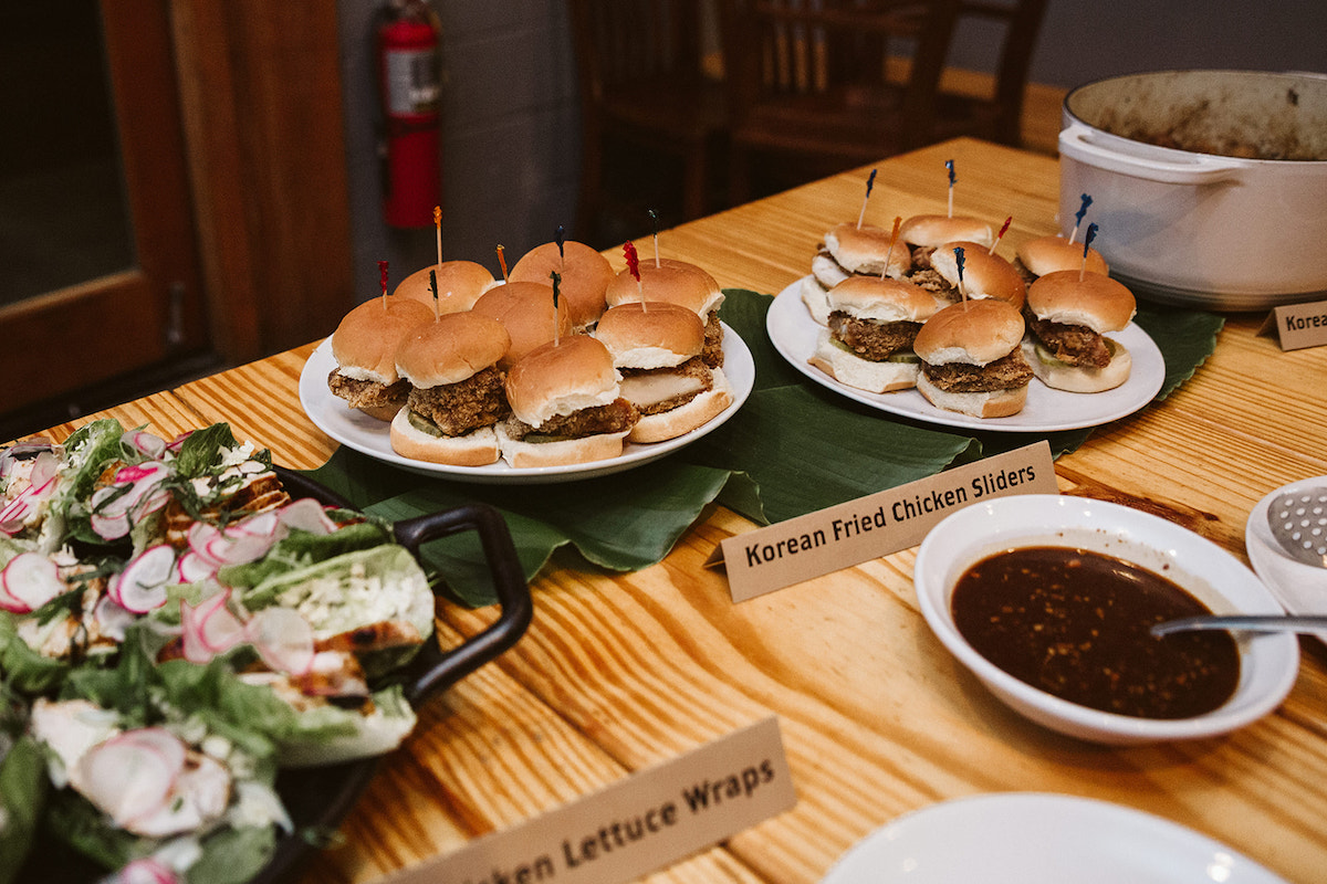 white buffet platters with chicken lettuce wraps and Korean fried chicken sliders and sauces