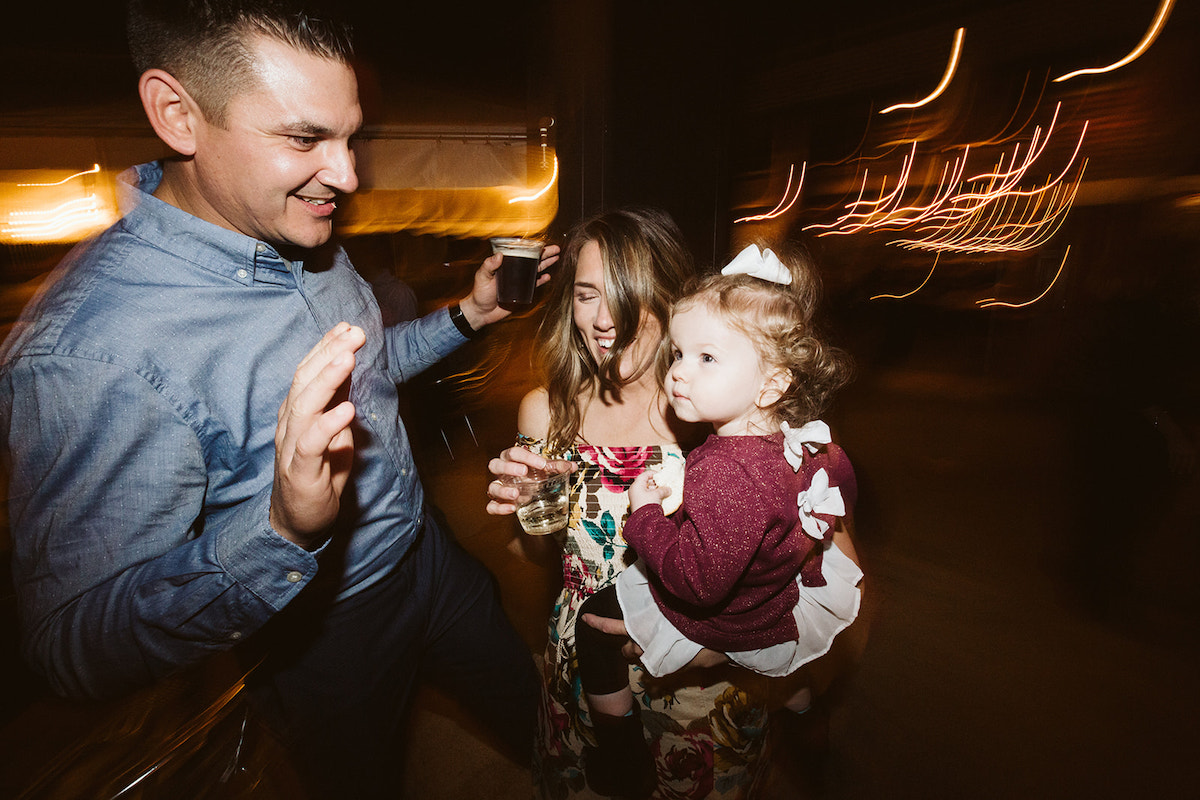 man and woman holding a toddler girl dance at an outdoor wedding reception