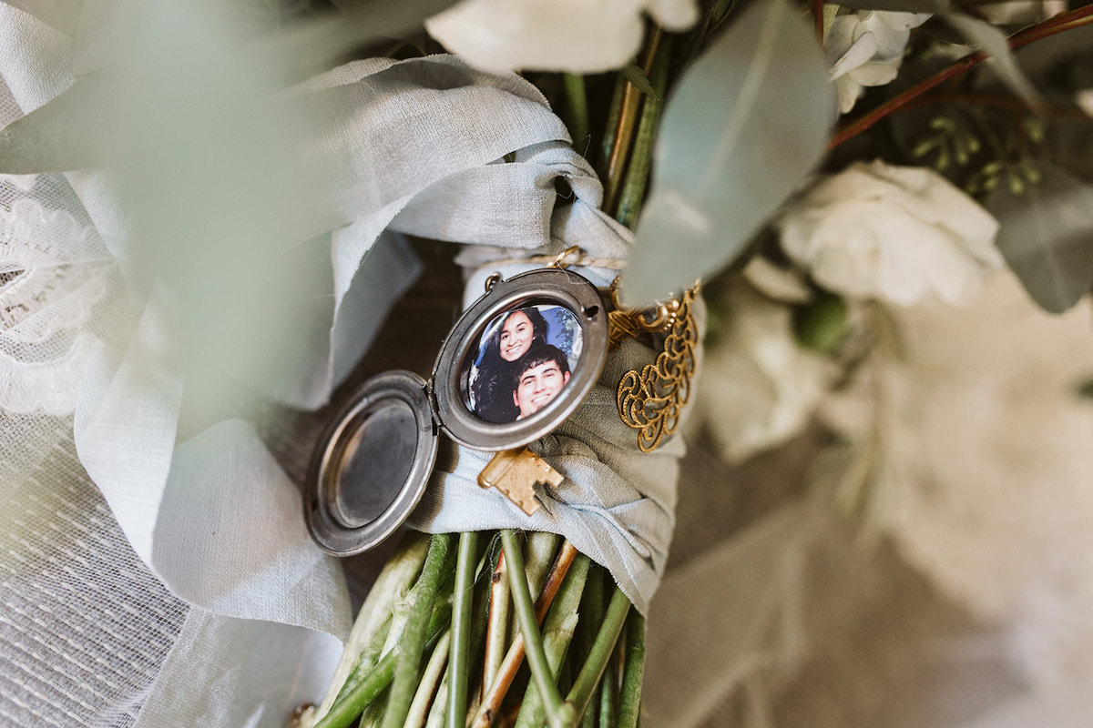 open locket with photo of young man and woman is tied to flower bouquet