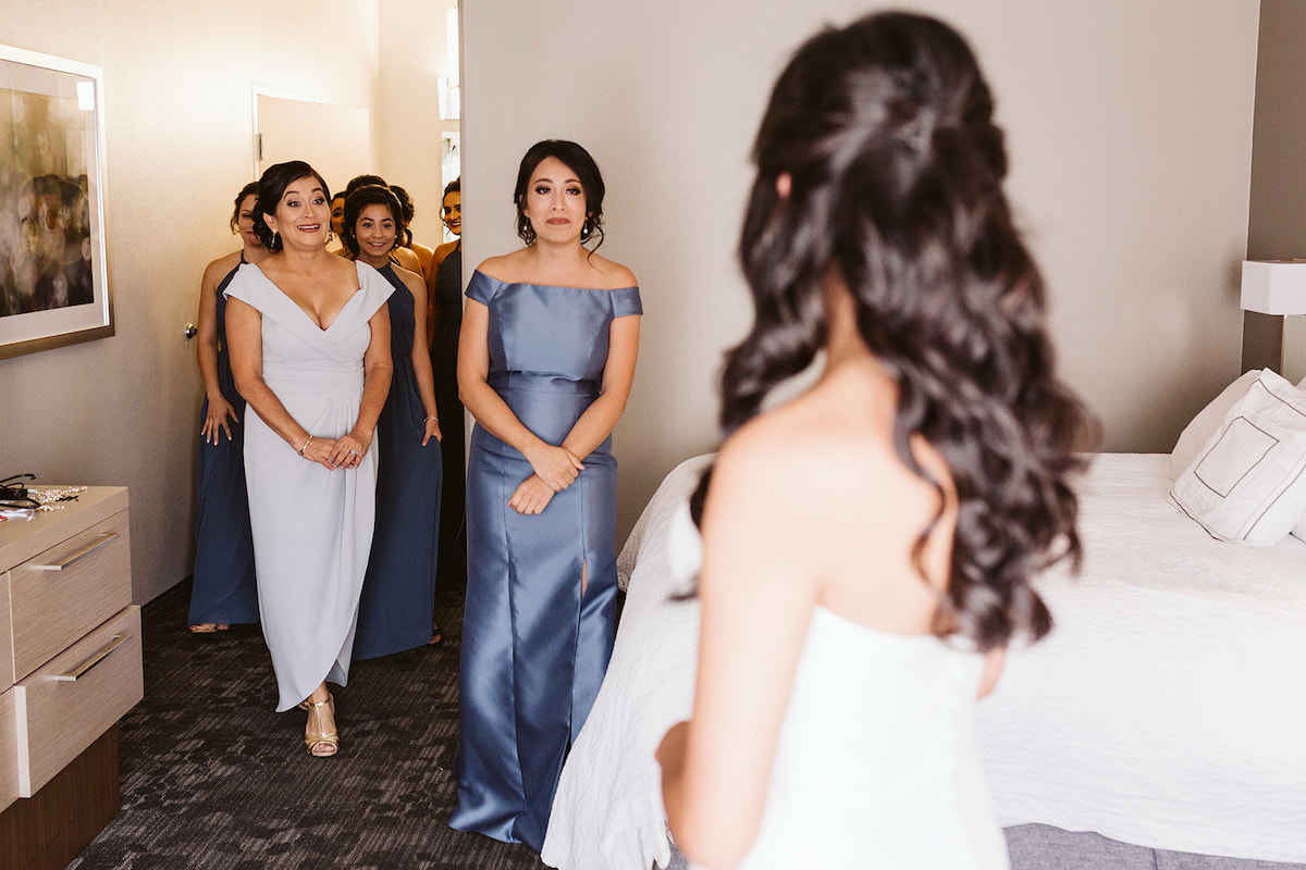 mother and bridesmaids smile as they see bride