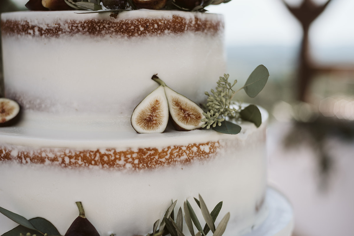 fig cut in half sits on one layer of white frosted naked cake