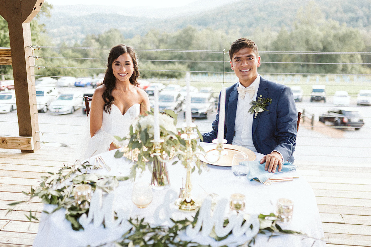 bride and groom sit at a private table smiling