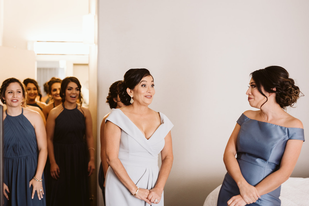 mother and bridesmaids smile as they see bride