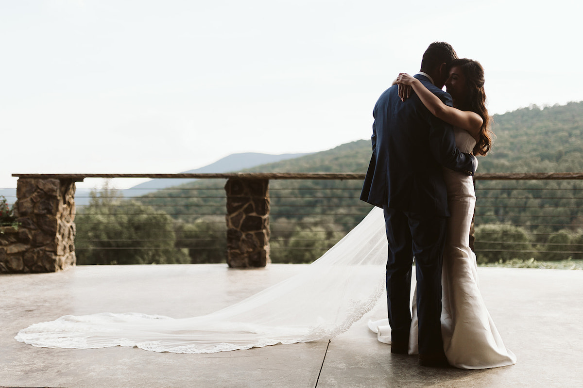 Bride and groom dance with their arms around each other with rolling hills of North Georgia in the background