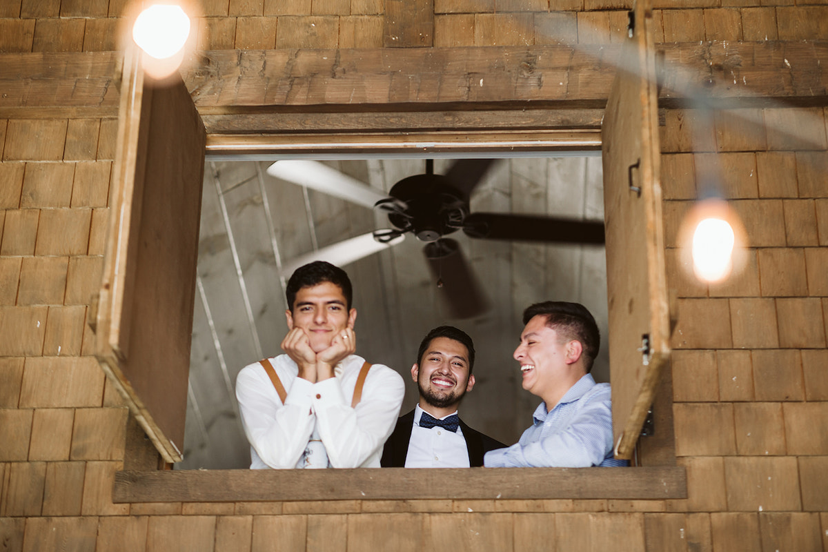 groom and friends peek out from upstairs window at DeBarge Vineyard