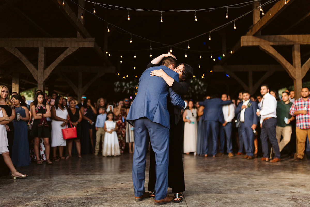 Groom and his mother hug and share a dance while wedding guests watch