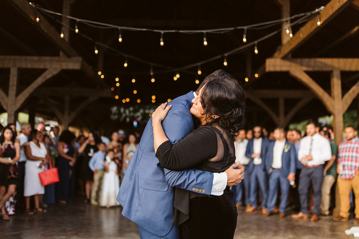 Groom and his mother hug and share a dance while wedding guests watch