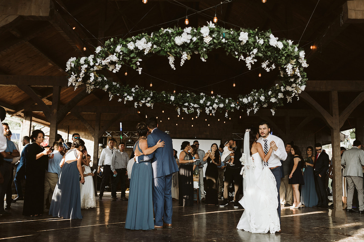 Bride and groom dance with friends during the Dollar Dance. They each have dollars pinned to their clothes