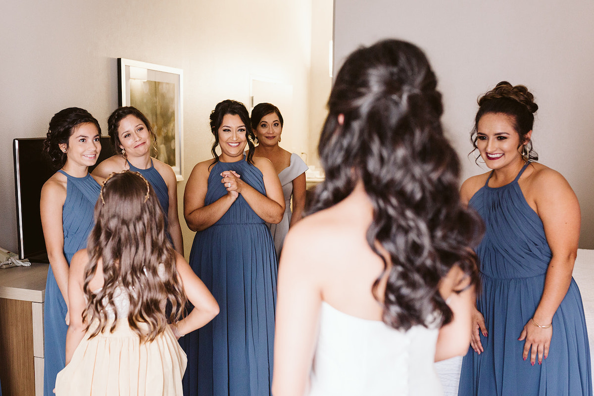 bridesmaids smile when they see bride in her dress