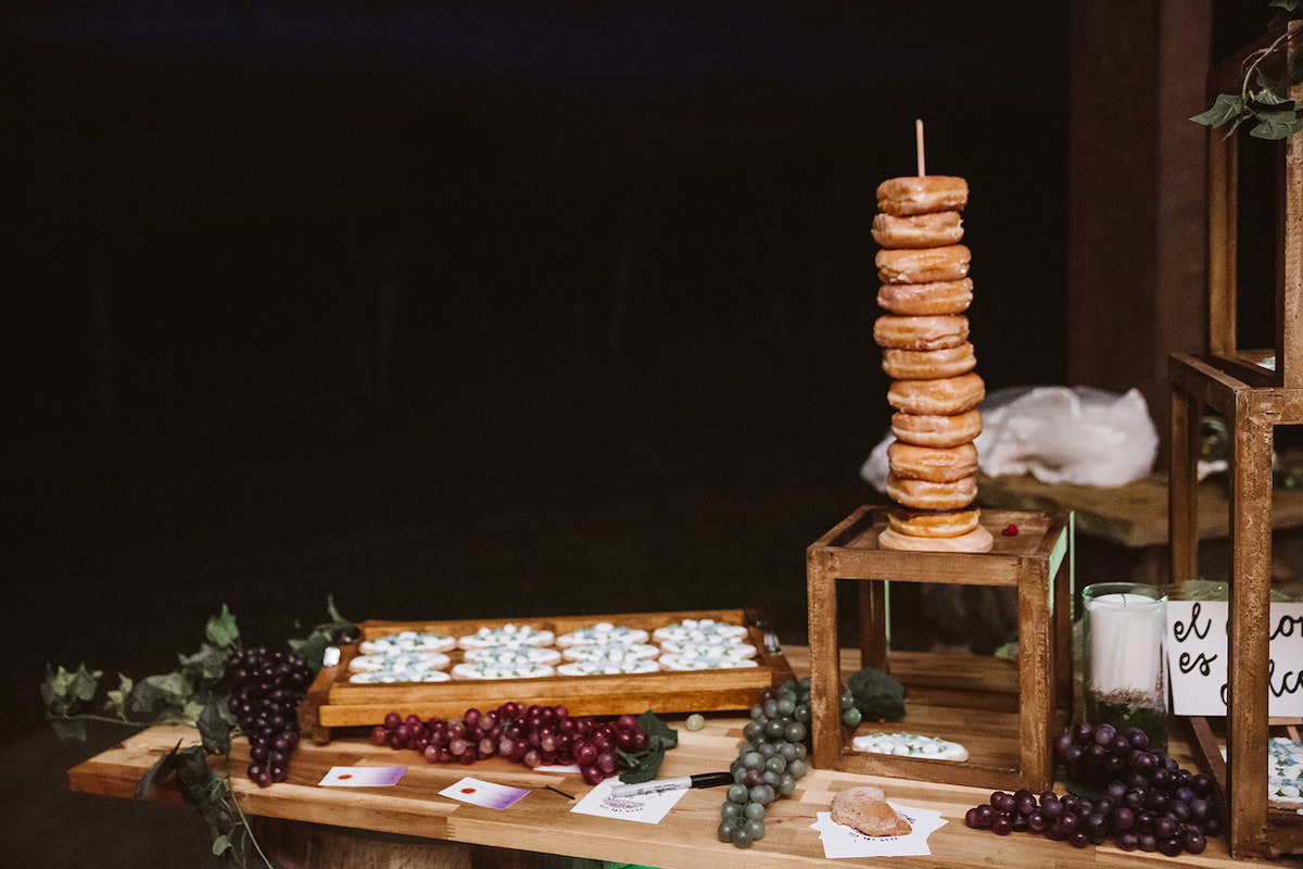 sugar cookies decorated with bride and groom initials on a platter next to vines of grapes