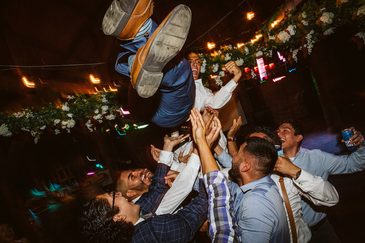 grooms friends throw him into the air as they dance