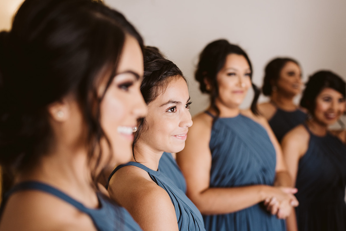 bridesmaids smile when they see bride in her dress