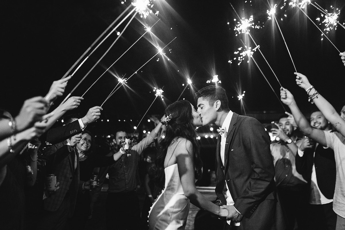 bride and groom kiss under sparkler tunnel after their wedding reception