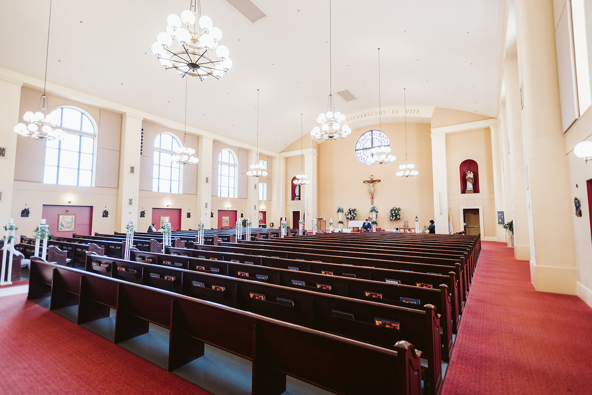 dark pews, red carpet, and bright interior of St Josephs Catholic Church in Dalton Georgia