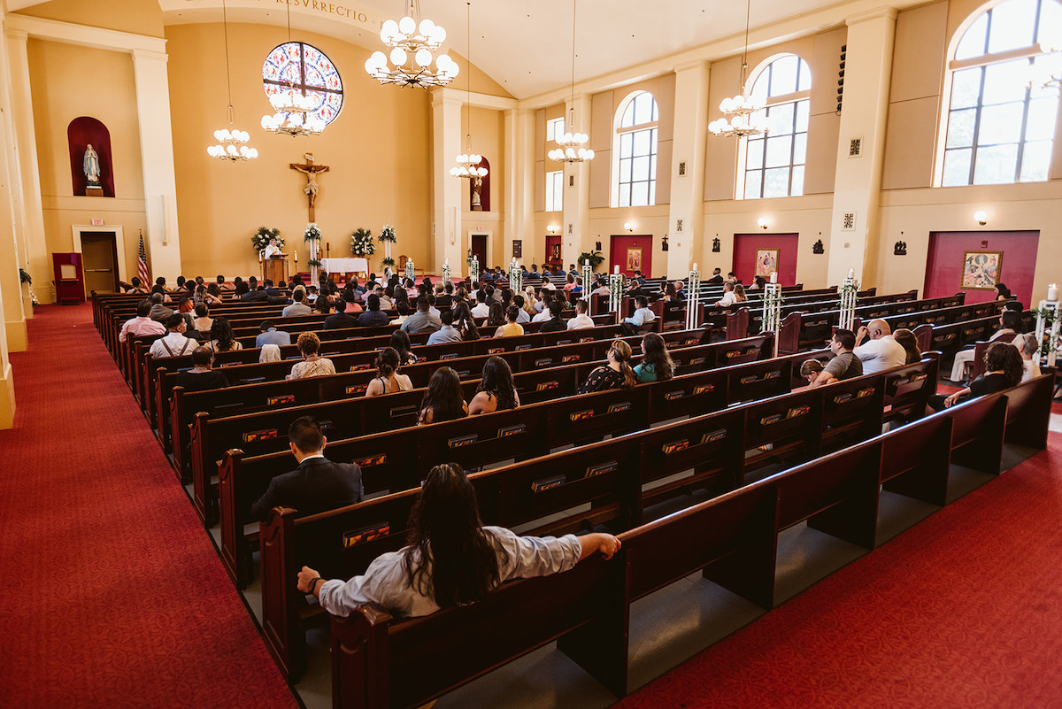 dark pews, red carpet, and bright interior of St Josephs Catholic Church in Dalton Georgia