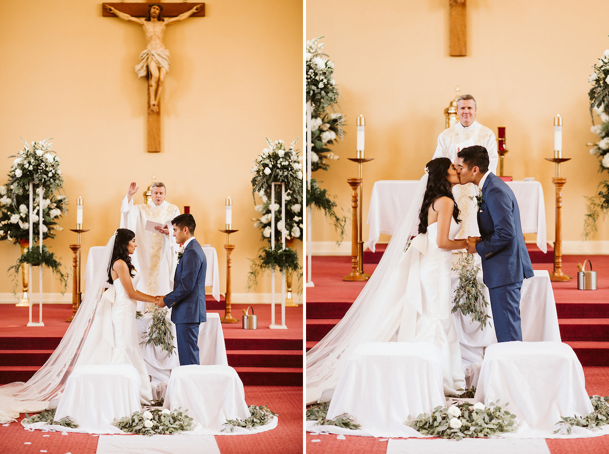 bride and groom hold hands and kiss while priest smiles at them