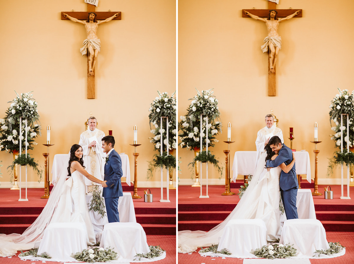 bride and groom hug while priest smiles at them