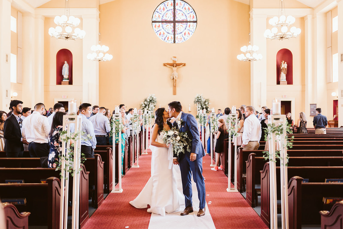 bride and groom kiss in the middle of the aisle at St Josephs Catholic Church in Dalton Georgia