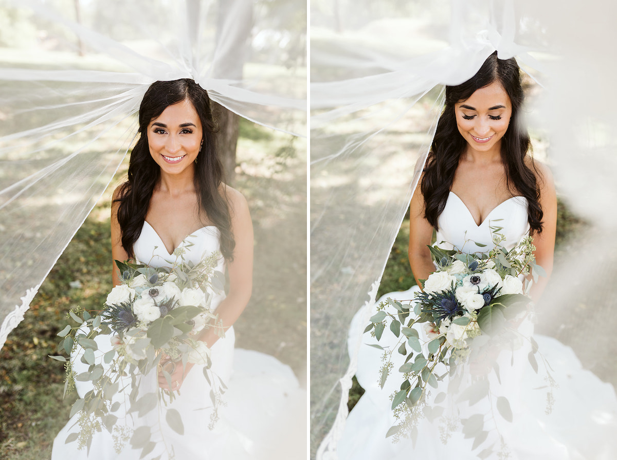 bride smiles and looks at her bouquet as her veil streams over her head