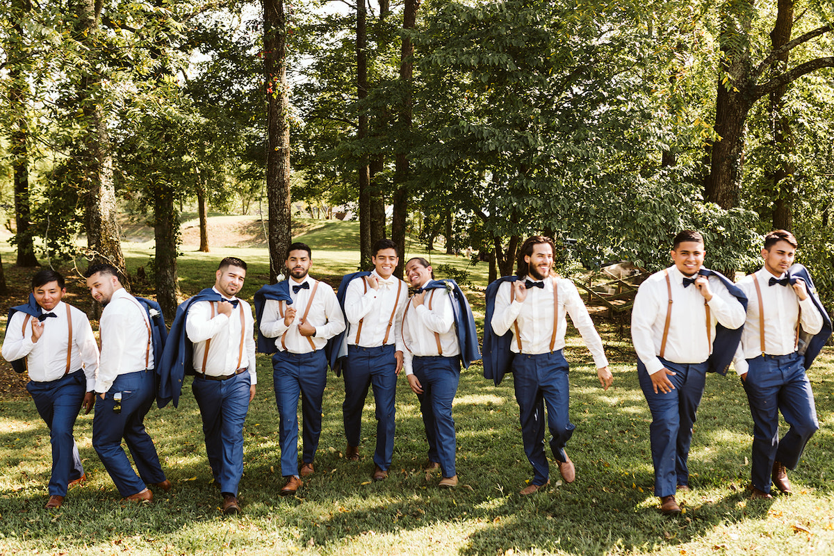 groom and groomsmen hold suit jackets over their shoulders