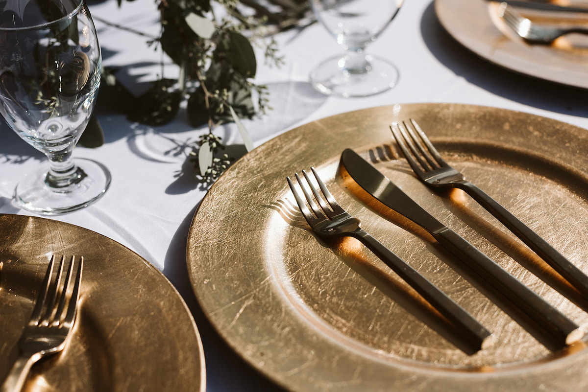 gold charger with two forks and a knife