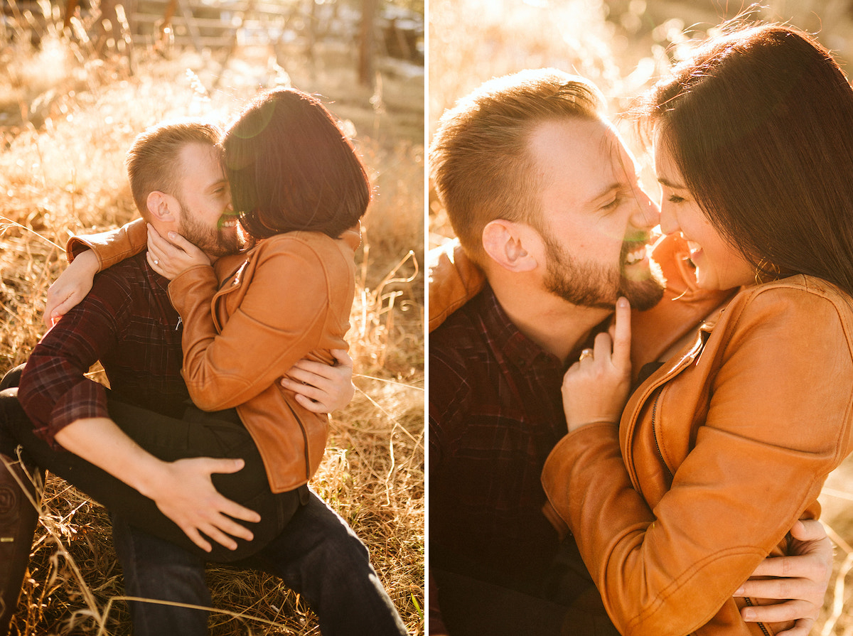 Man sits in tall golden grass with woman cuddling on his lap. She hugs one arm around his shoulder and leans toward him.