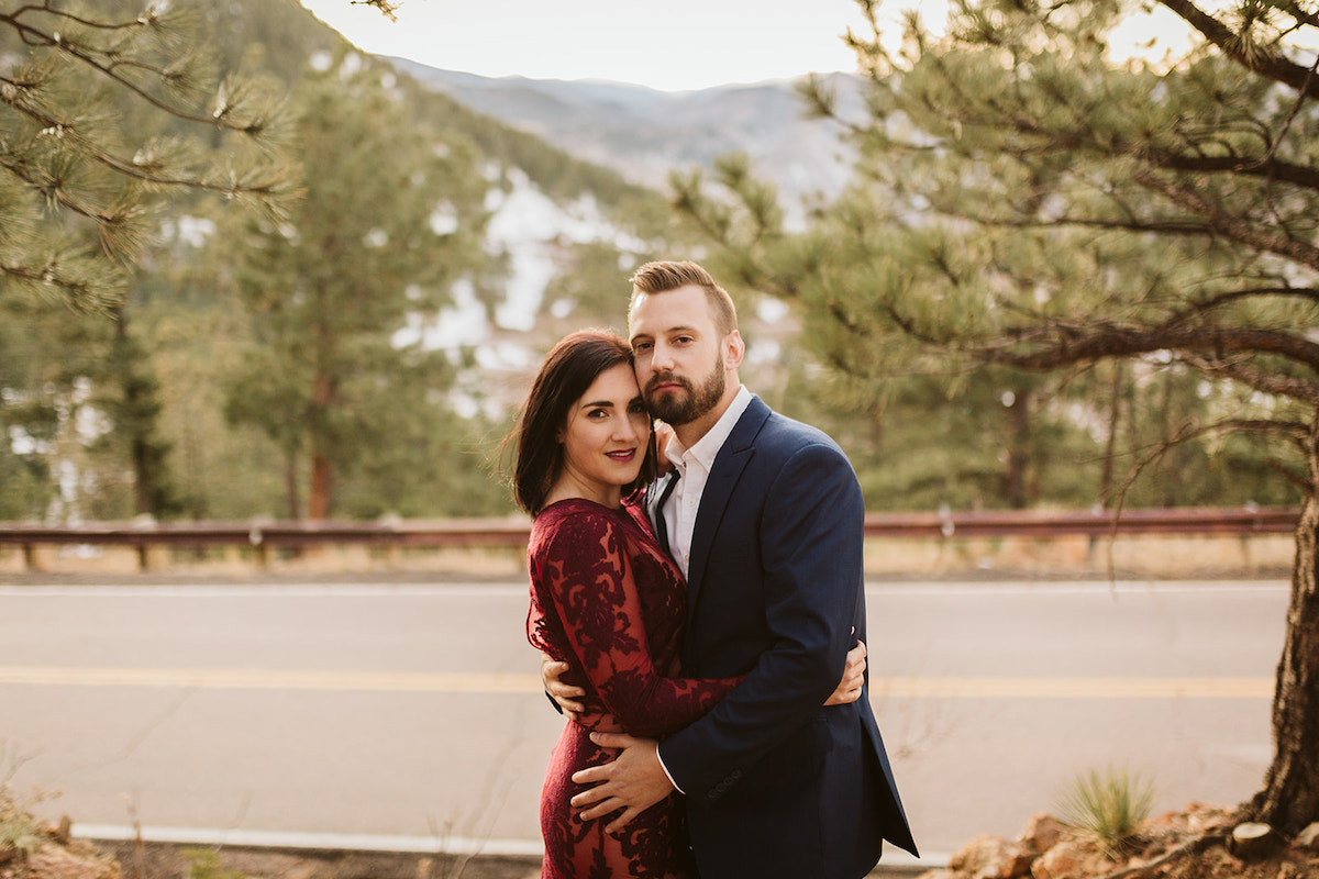 Man in dark suit and woman in maroon dress hug