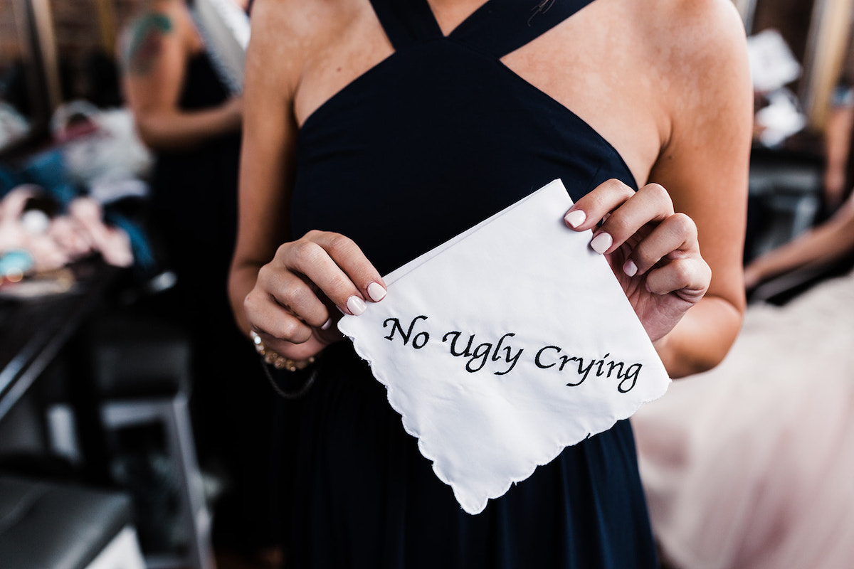 woman in black dress holds a handkerchief stitched with message No Ugly Crying